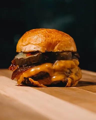 Double cheeseburger with bacon on a brioche bun, on a wooden board