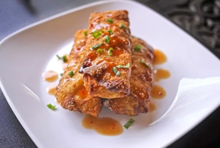 Egg roll glazed in sauce on a white plate