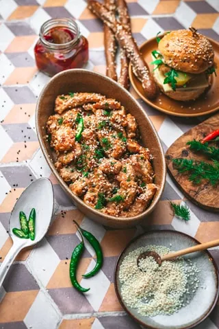 Baked shredded chicken in a dish with sesame seeds and green chillies