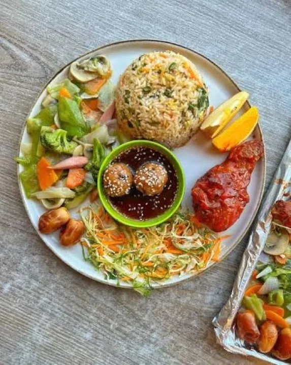 Rice, salad and a meatball in a lime shell with chilli sauce