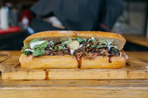 Steak sandwich in a long roll on a wooden board