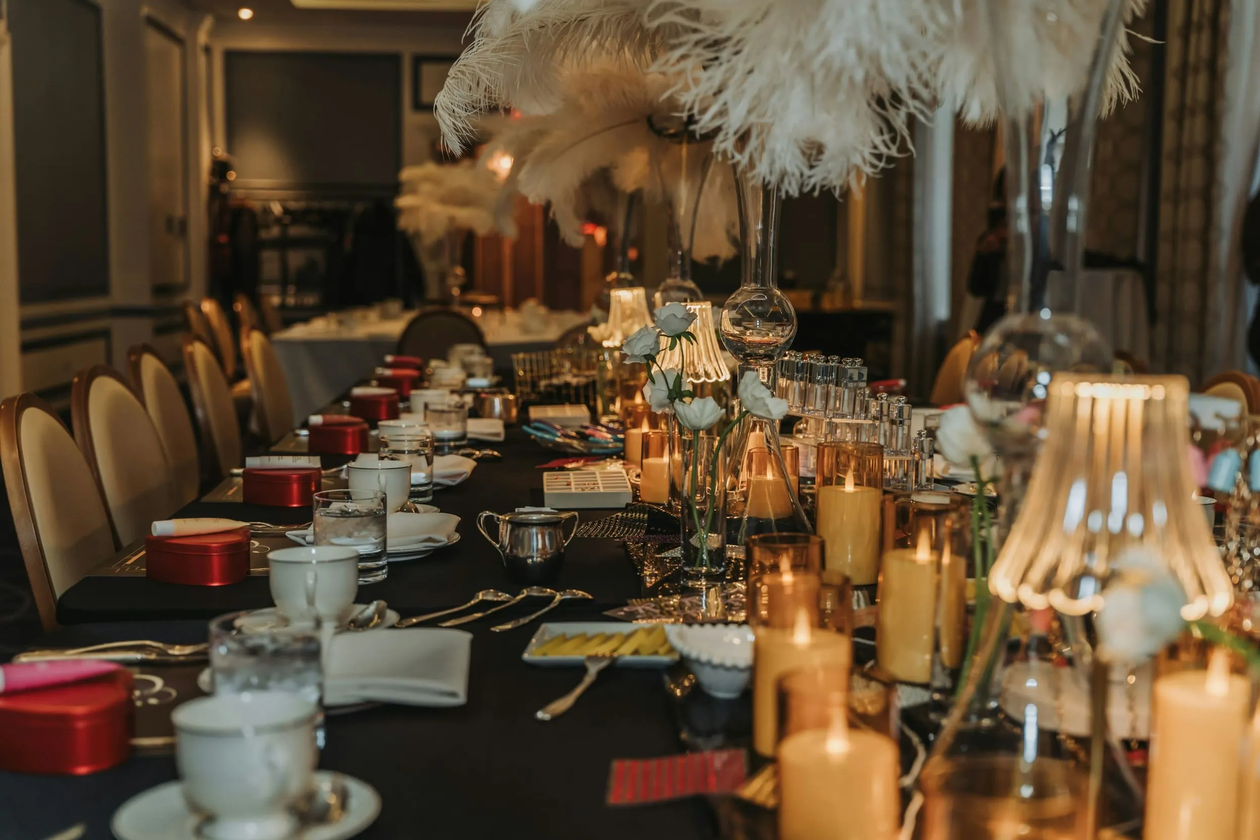 A long banquet table laid with candles, glassware and place settings